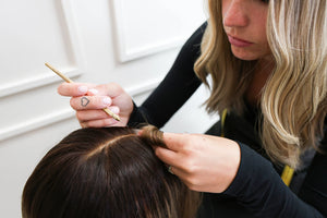 Beka Wigs stylist hand-finishing the parting of a brown human hair wig with a ventilating needle