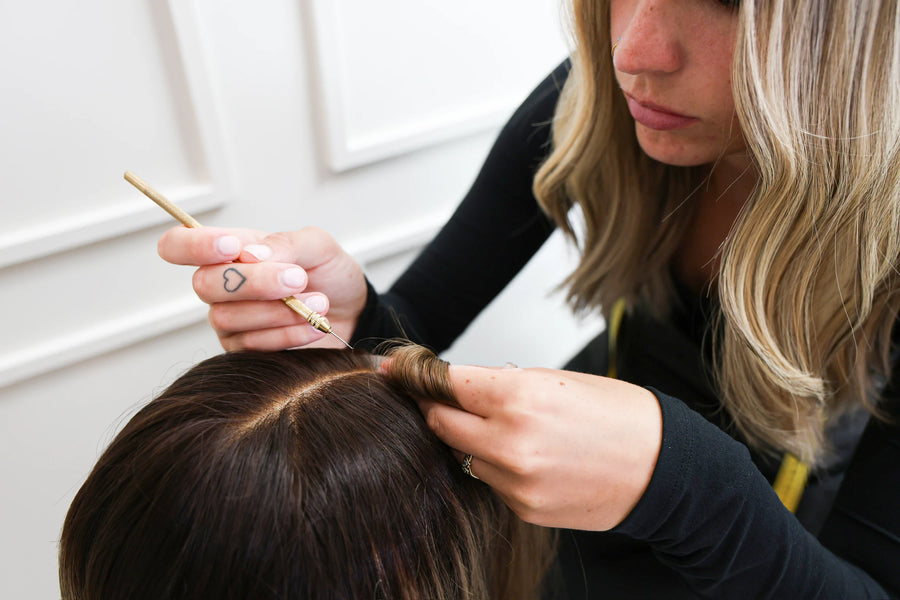 Beka Wigs stylist hand-finishing the parting of a brown human hair wig with a ventilating needle