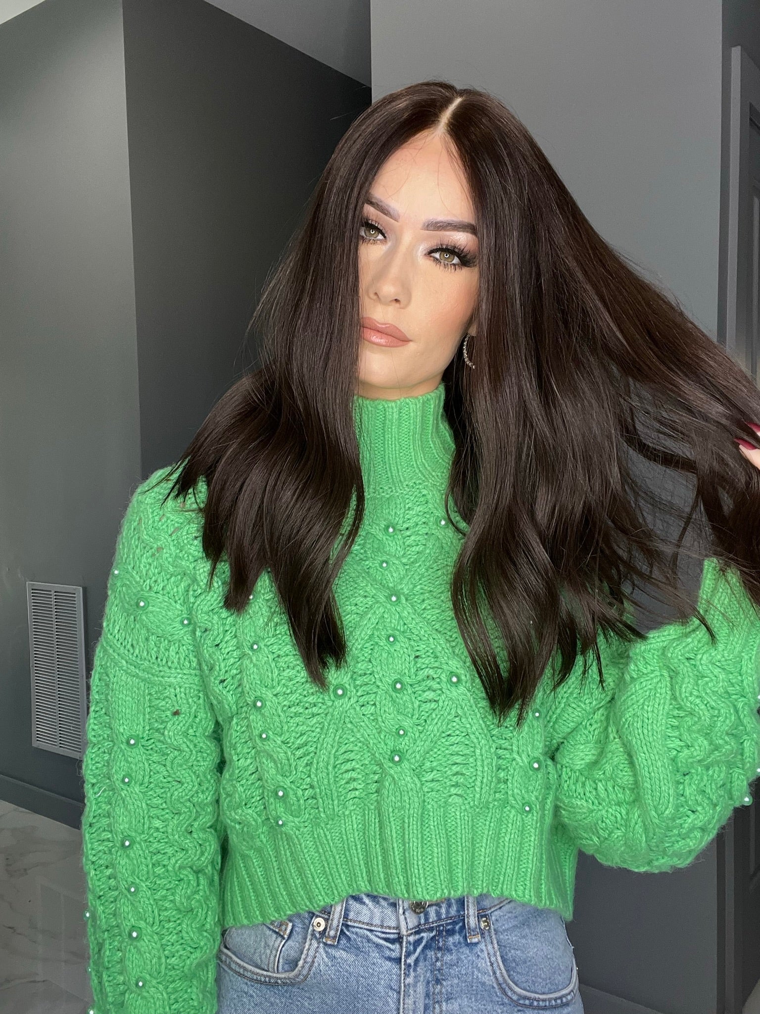 Long dark brown human hair wig with loose waves, styled with middle part, worn by model in green sweater