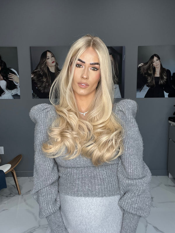 Blonde human hair wig with voluminous waves, lace top, and natural-looking part for a glamorous look.